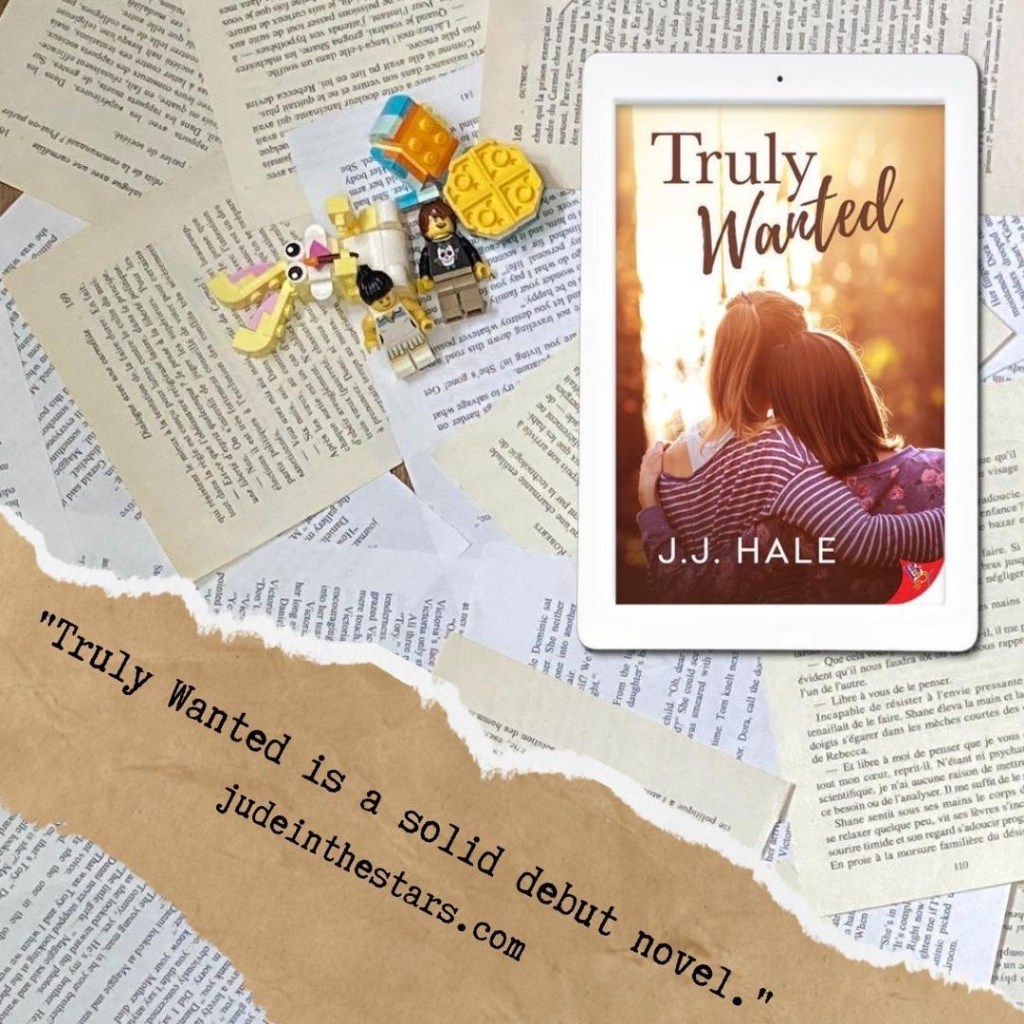 On a backdrop of book pages, an iPad with the cover of Truly Wanted by J.J. Hale, next to a few LEGO bricks and figures. At the bottom of the image, on the left-hand side, a strip of torn paper with a quote: "Truly Wanted is a solid debut novel" and a url: judeinthestars.com