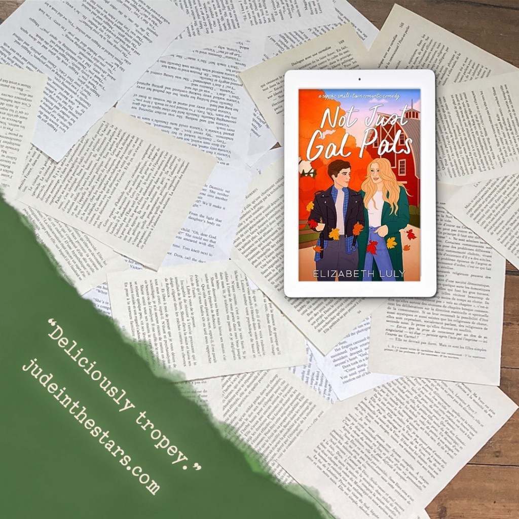 On a backdrop of book pages, an iPad with the cover of Not Just Gal Pals by Elizabeth Luly. In the bottom left corner of the image, a strip of torn paper with a quote: "Deliciously tropey." and a URL: judeinthestars.com.