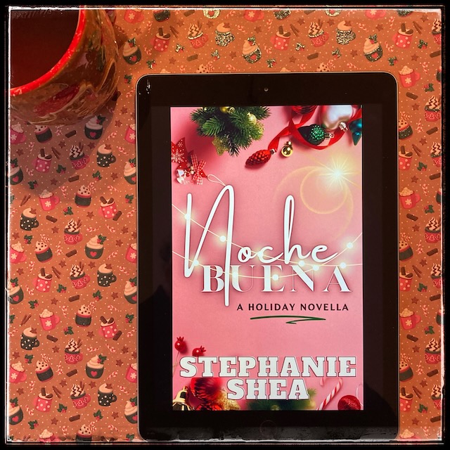 On a cheery Xmas background with mugs of hot drinks, an iPad with the cover of Nochebuena by Stephanie Shea, next to a gingerbread man mug.