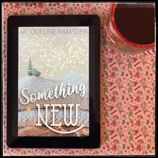 On a cheery Xmas background, an iPad with the cover of Something New by Jacqueline Ramsden, next to a gingerbread man mug.