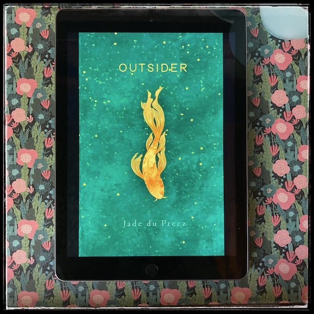 On a background featuring Japanese-inspired flowers in subdued pink and blue, an iPad with the cover of Outsider by Jade Du Preez.