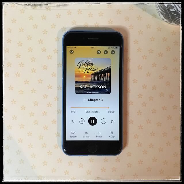 On a sunny background, an iPhone with the cover of Golden Hour by Kat Jackson, narrated by Lila Winters.